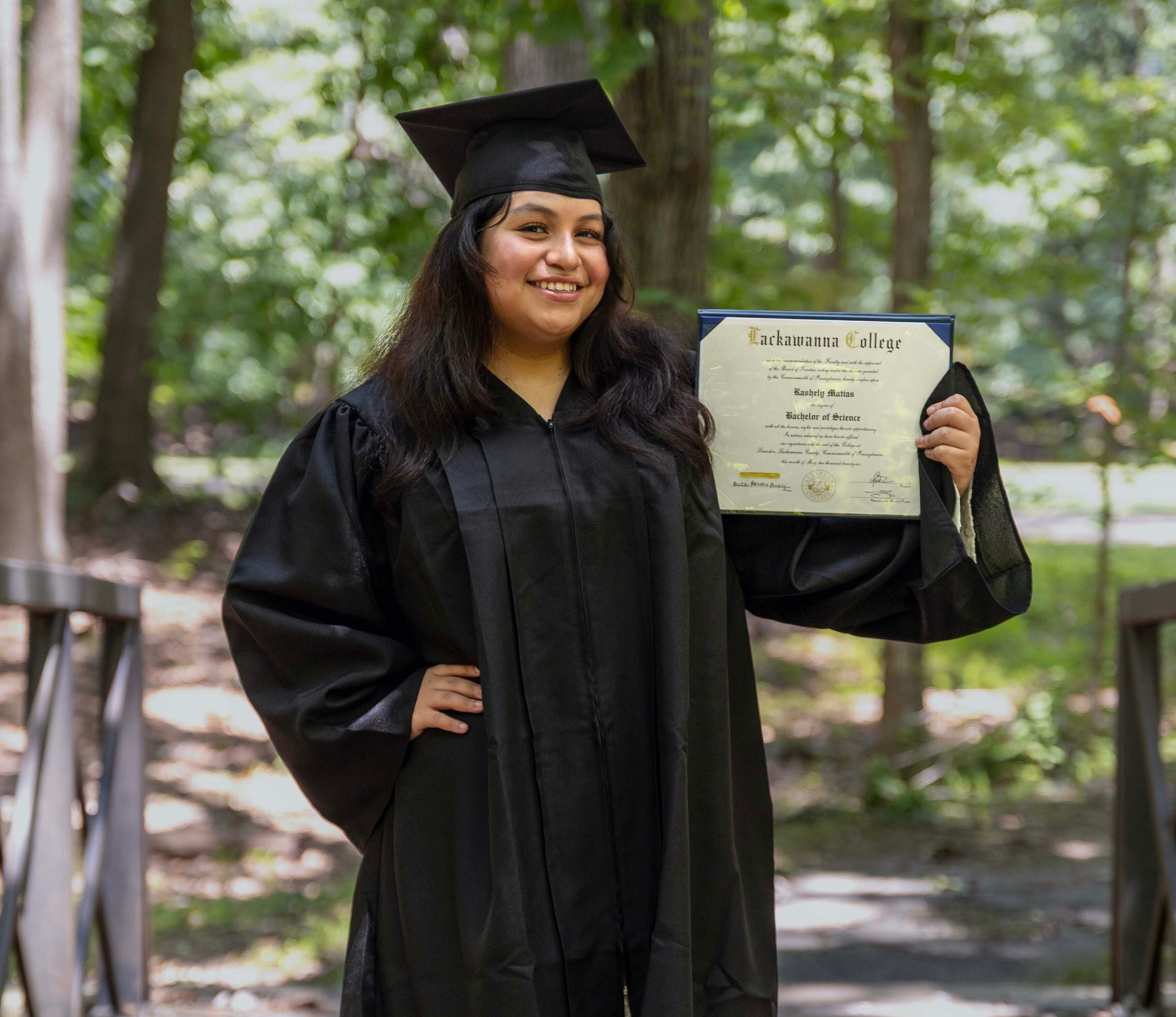 Rashely Matias at her college graduation holding her Bachelor of Science diploma